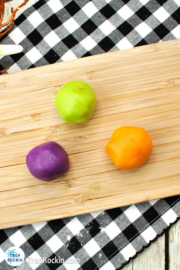 Three balls of colored dough on cutting board.