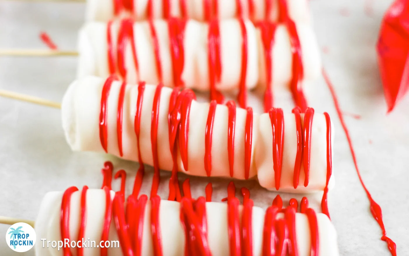 Marshmallow pops drizzled with melted red candy melts.