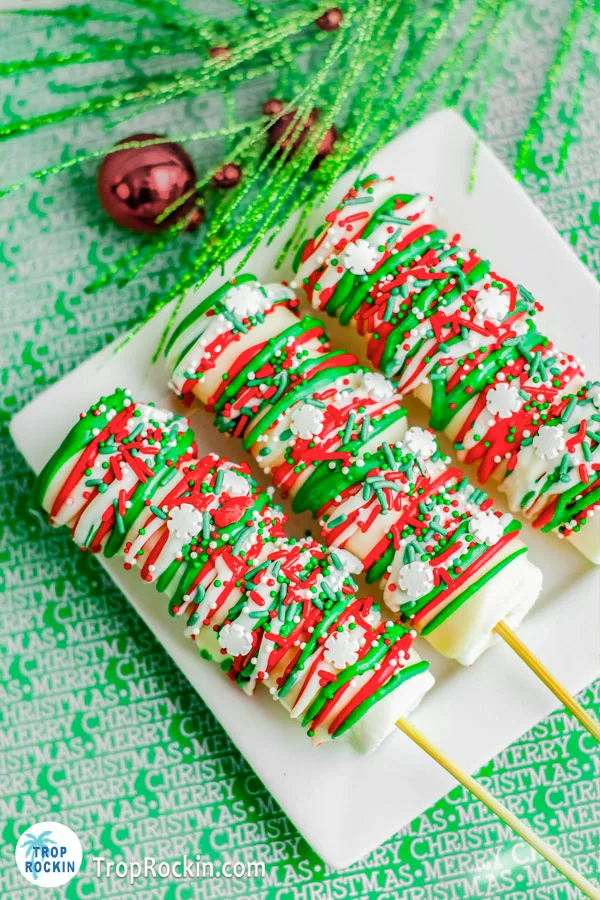 Three Christmas marshmallow pops on a white plate.