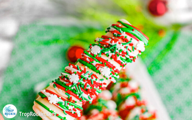 Christmas Marshmallow Pop covered in white chocolate and drizzled with red and green melted candy topped with Christmas sprinkles.