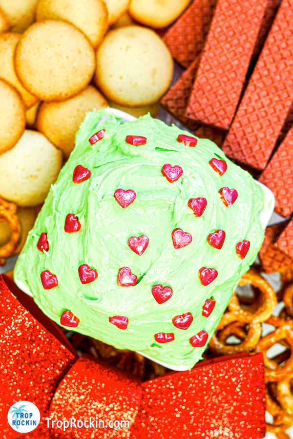 Bowl of Grinch Dip with red hearts on cookie platter.