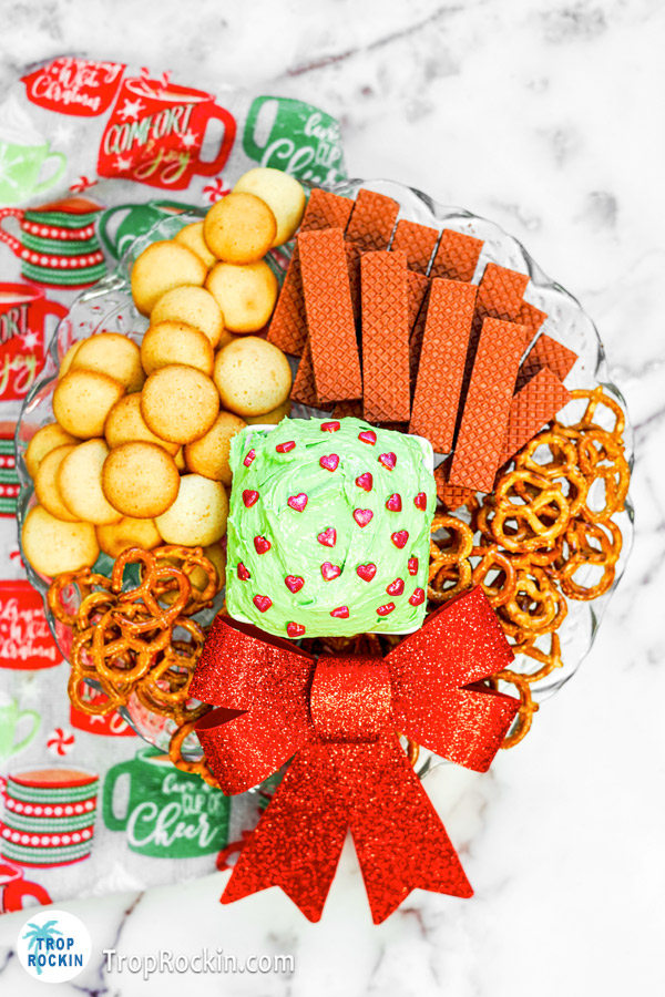 Full platter of cookies, waffers and pretzels with Grinch dip in a bowl in the center.