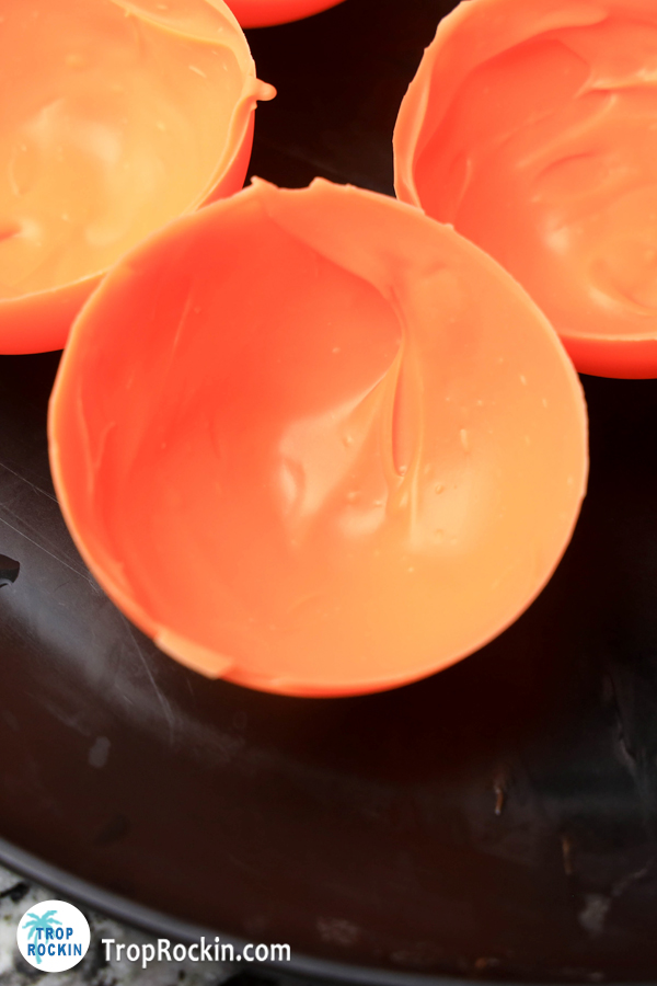 Orange chocolate sphere sitting on black cold plate.