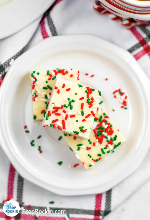 Top view of 3 squares of christmas cookie fudge on a white plate.