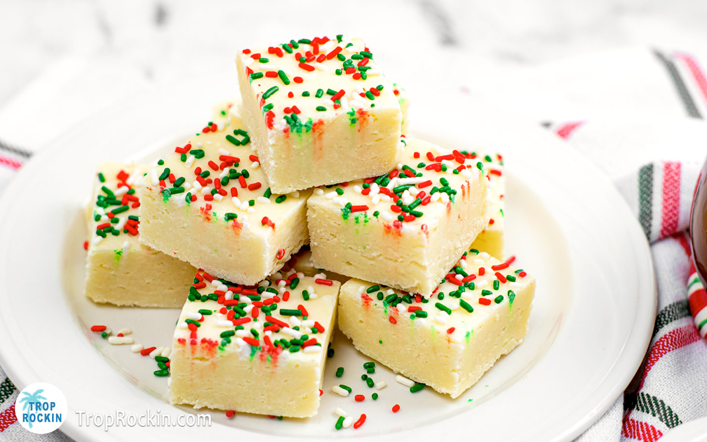 Large white plate of Christmas Cookie Fudge squares stacked.