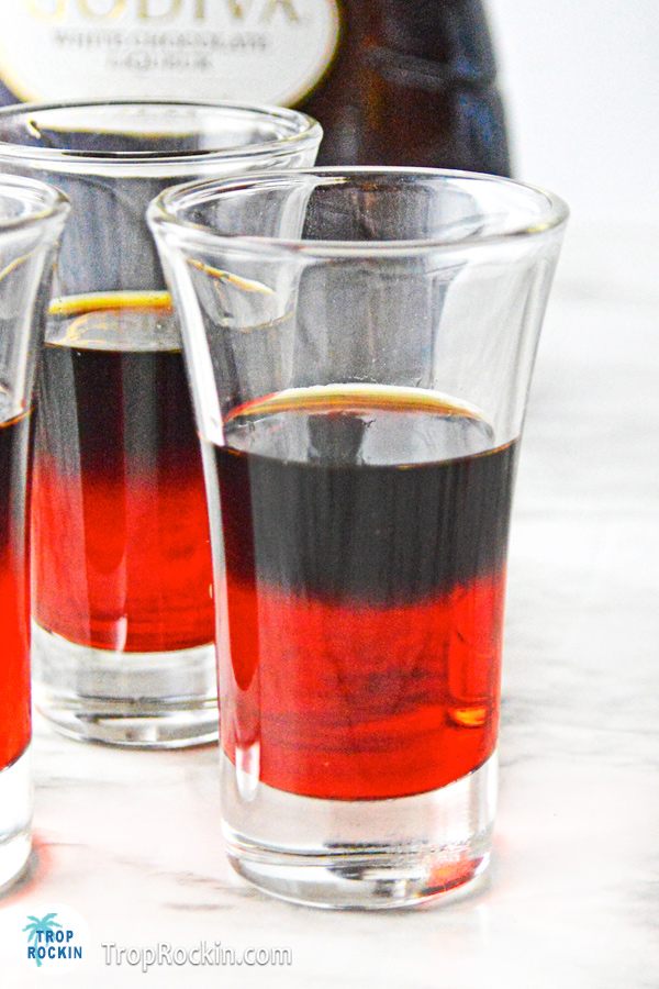 Kahlua poured on top of the grenadine in a shot glass making a black layer.