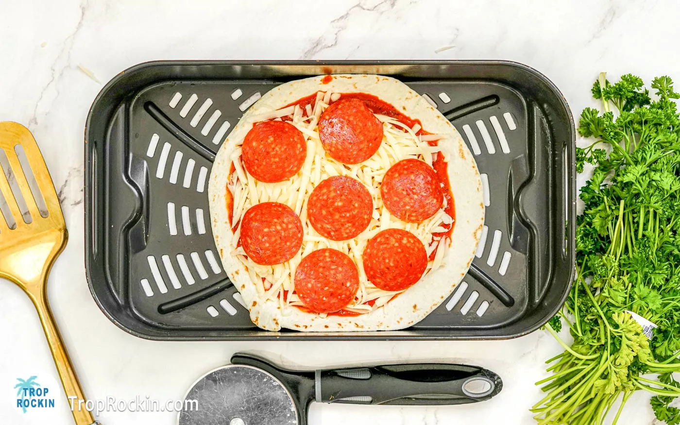 Tortilla pizza in the air fryer basket.