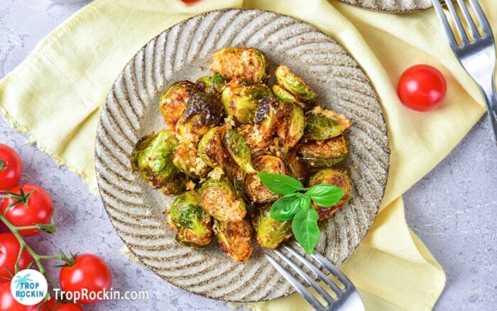 Plate of crispy air fryer Brussels sprouts seasoned and covered with grated Parmesan cheese.