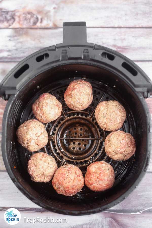 Raw meatballs inside the air fryer basket.