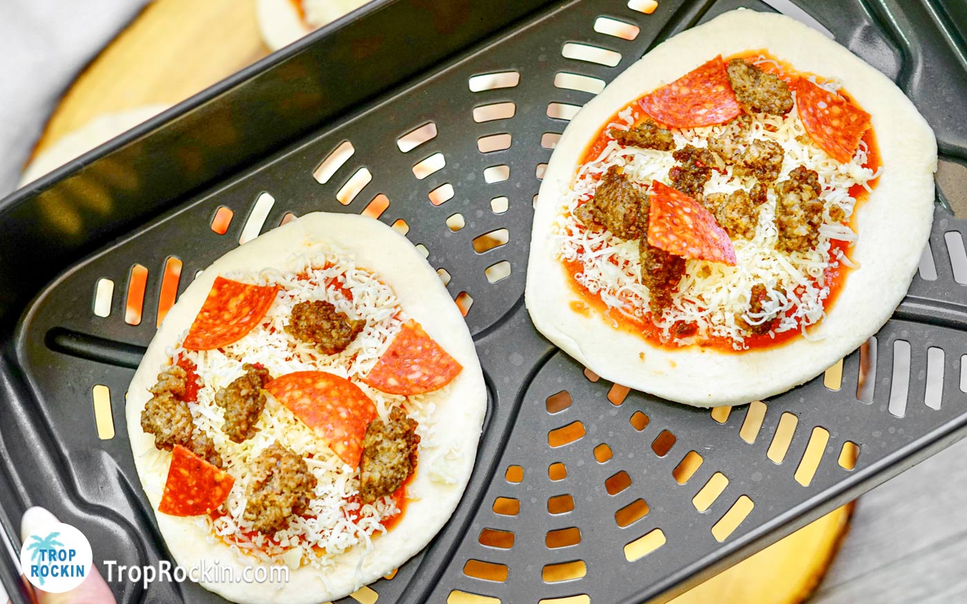 Two mini pizzas in air fryer basket.