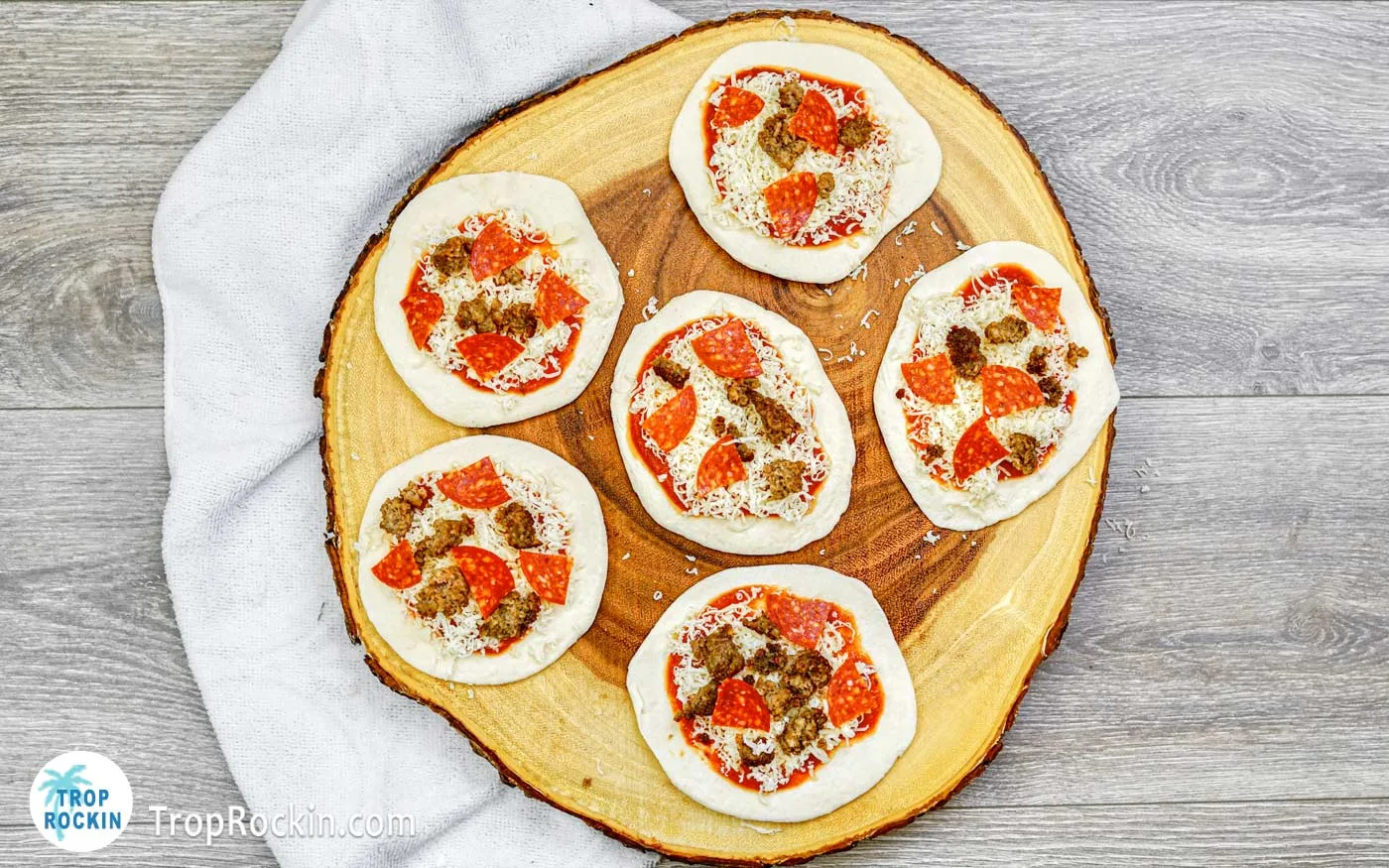Six mini pizzas with added mozzarella cheese, pepperoni and sausage.