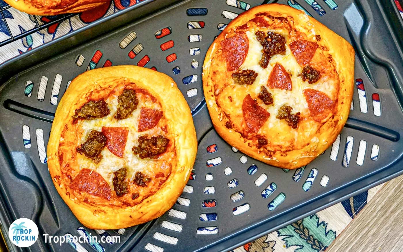 Two air fried mini pizzas in the air fryer basket.