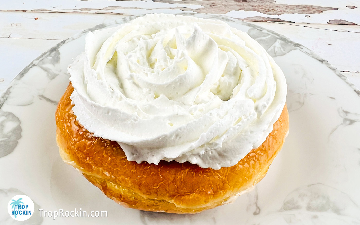 Glazed donut with a layer of whipped cream added on top.