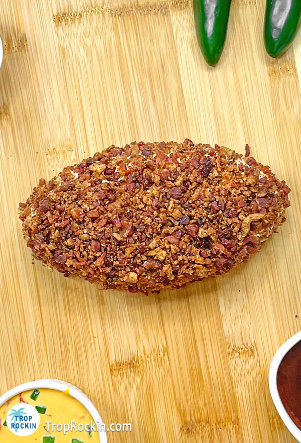 Football shaped cheese ball in center of the charcuterie board.