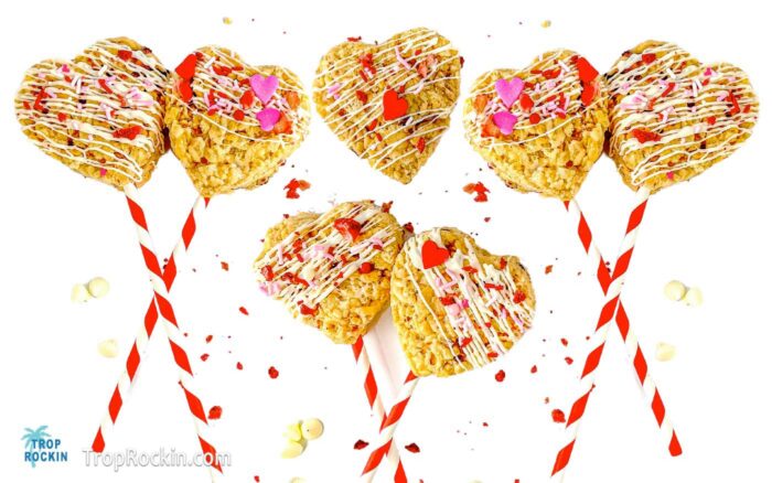 Decorated heart shaped rice krispie treats with red and white straws attached to make them into heart pops for a Valentine's Day Treat.