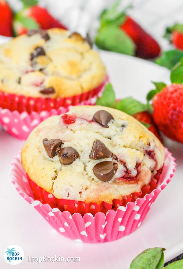 Focus on a single chocolate chip strawberry muffin in a cupcake liner with another muffin in the background.