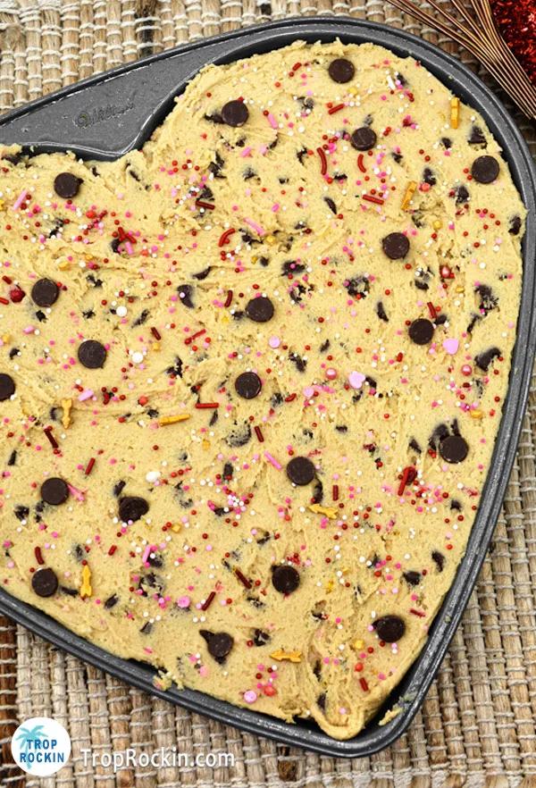 Raw chocolate chip cookie dough in heart-shaped pan.