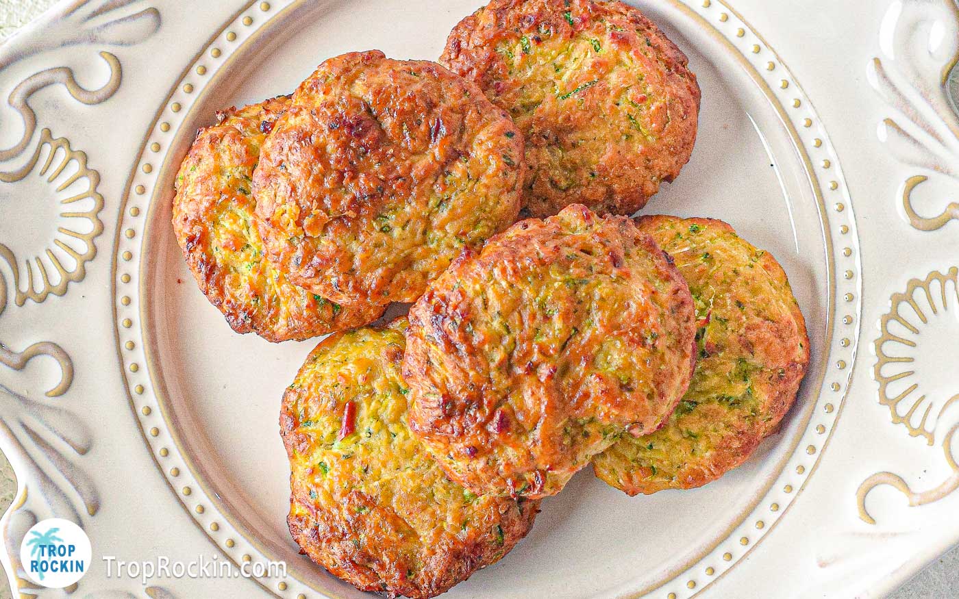 Air Fryer zucchini fritters in a pile on a white plate.