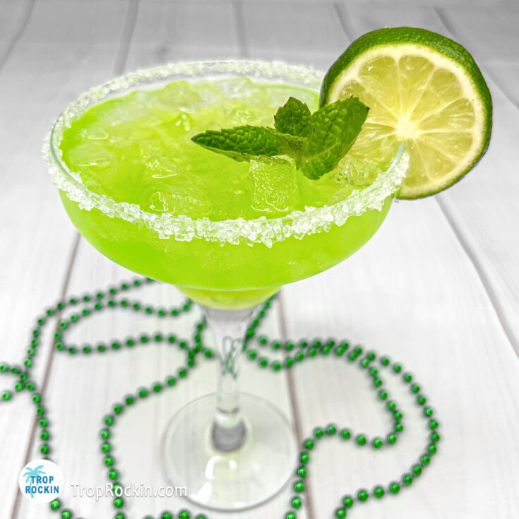 Irish Margarita in a margarita glass on white background with mint and lime wheel for garnish.