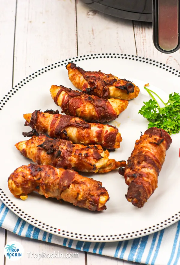 White plate full of air fryer bacon wrapped chicken tenders.
