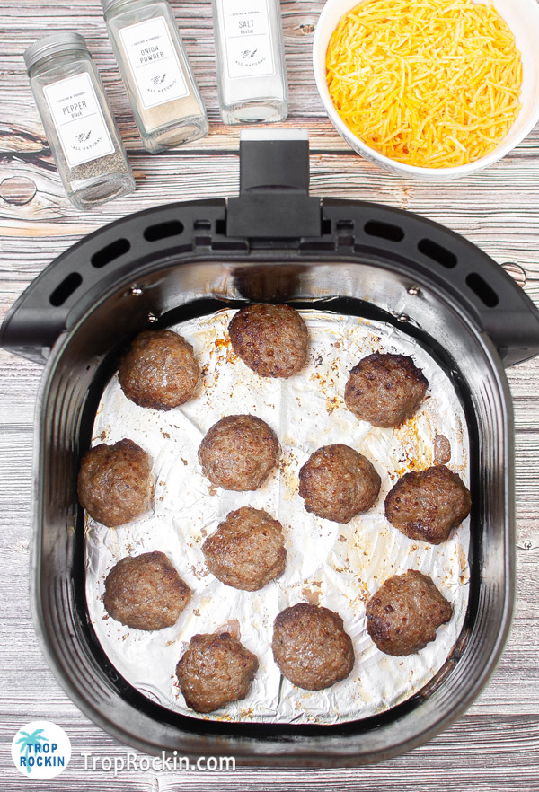 Cooked sausage patties in the air fryer basket.