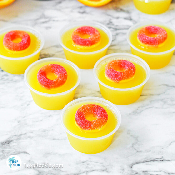 Set of 6 fuzzy navel jello shots on counter top.