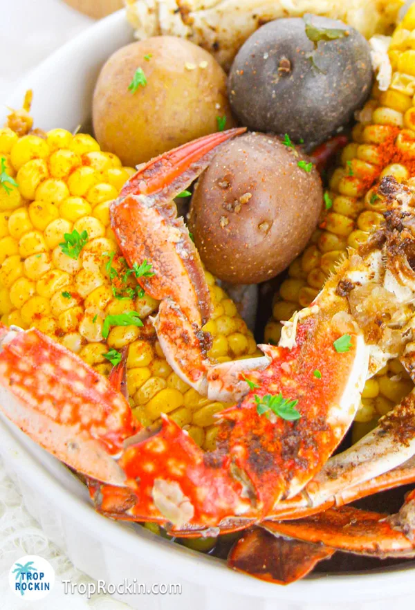 Up close photo of a bowl of crab boil showing corn, potatoes and crab.