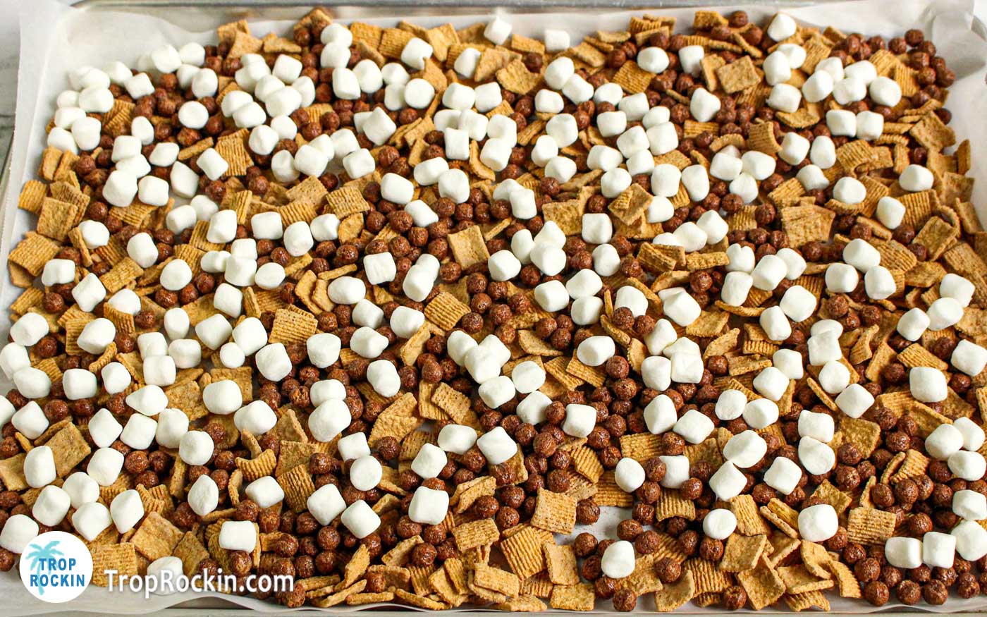 Baking sheet covered in parchment paper with Golden Grahams cereal, Coco Puffs cereal and mini marshmallows.