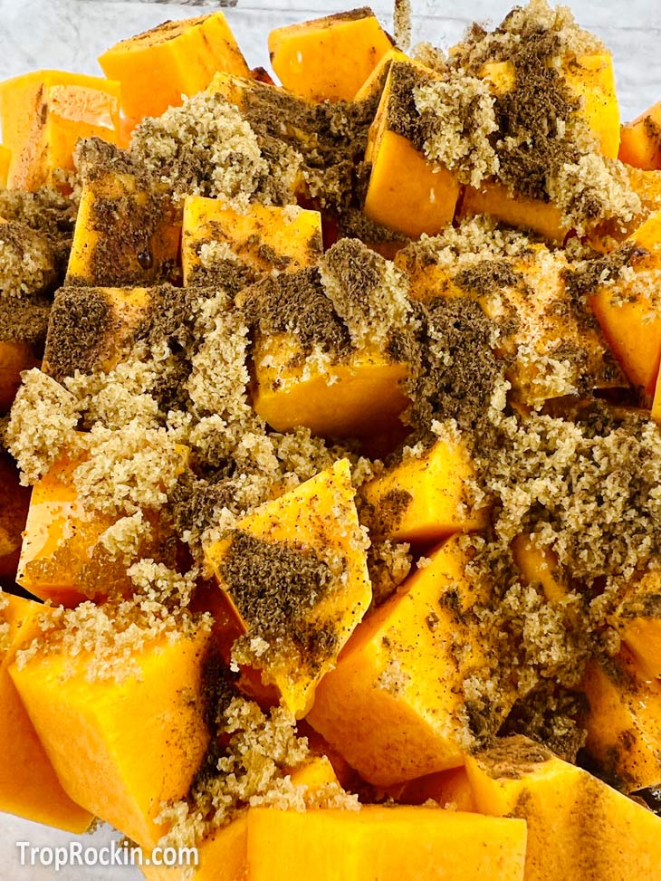 Pile of Butternut squash cubed with added spices and brown sugar on top.