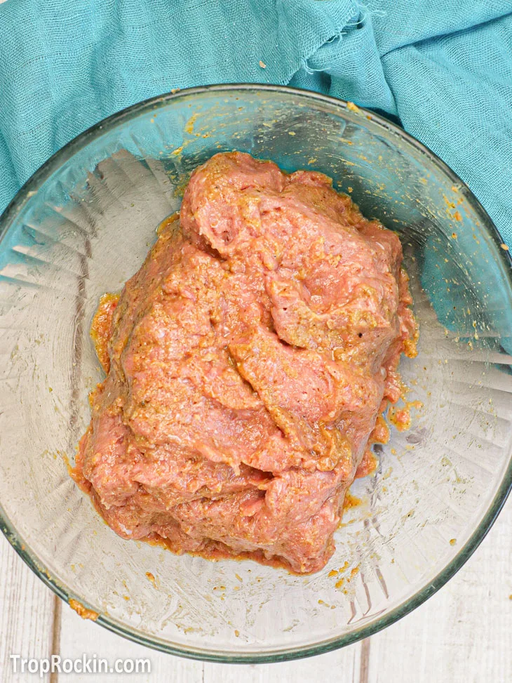 All air fryer meatloaf ingredients combined in a clear bowl and shaped into a meatloaf.