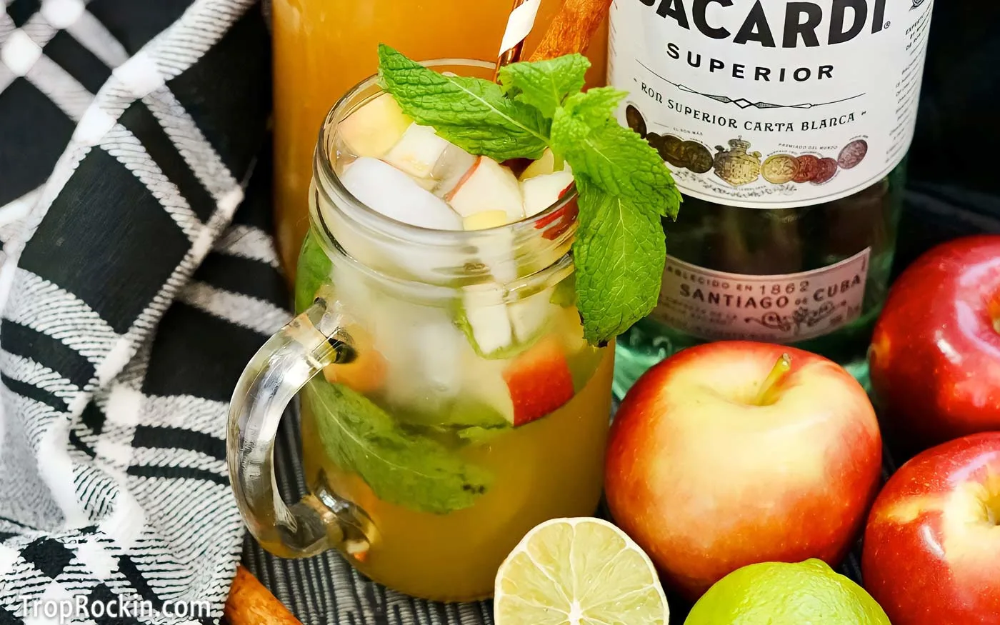 Apple cider mojito with apples, limes, bottle of rum and caraft of apple cider.