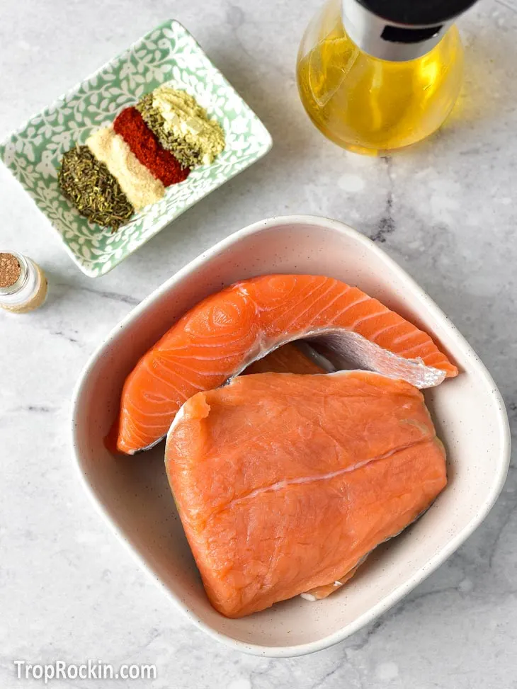 Air Fryer salmon bites ingredients displayed in bowls on counter top with an bottle of olive oil.