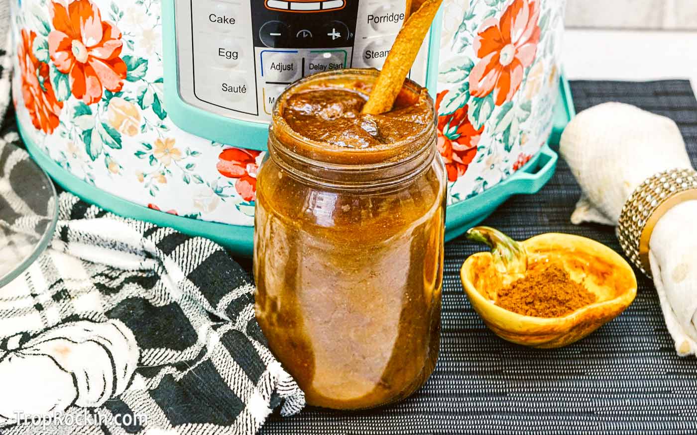 Mason jar filled with instant pot pumkin butter with a cinnamon stick on top.