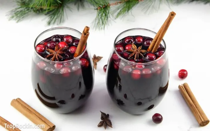 wo glasses of slow cooker mulled wine with cranberries, cinnamon stick and star anise for garnish.