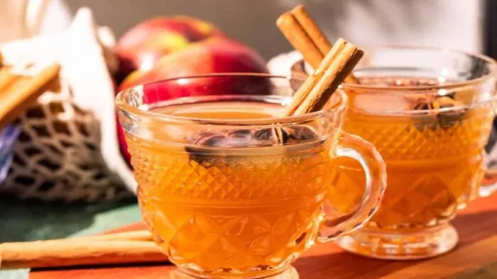Mugs of cider toddy with anise and cinnamon sticks.