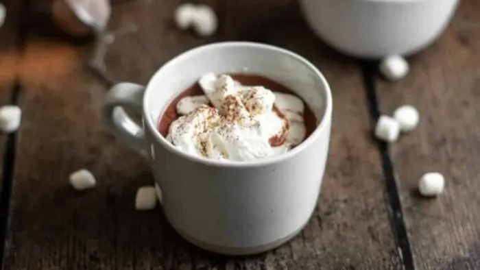 Mugs of red wine hot cocoa with marshmallows over the top.