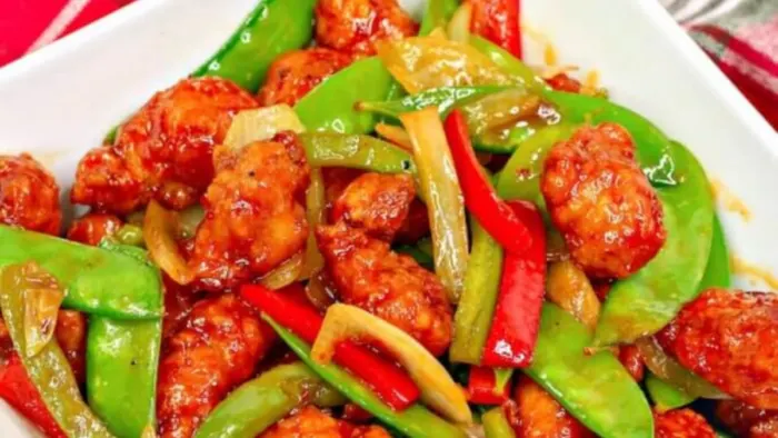 A plate of spicy saucy chicken and peppers.
