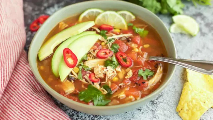 Chicken Tortilla Soup in a bowl with slices of avocado on top.