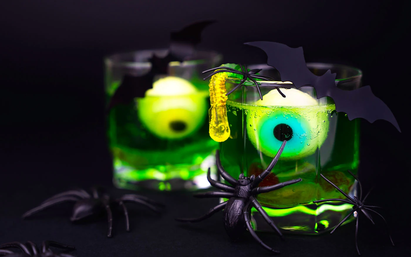 Two green halloween jello shots with gummy eyeballs.