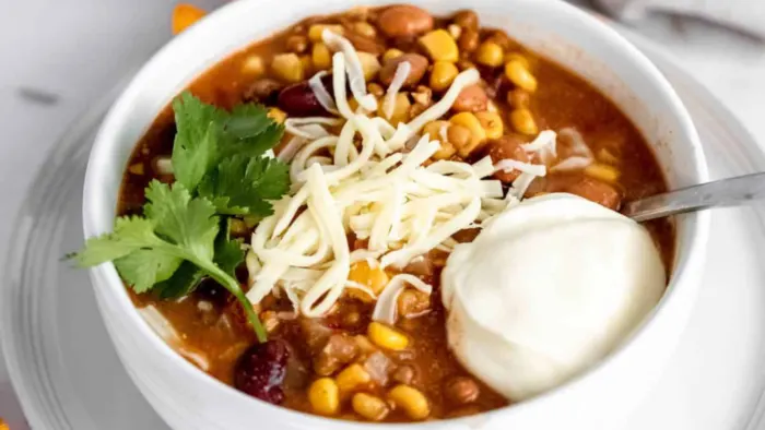 Bowls of taco soup with beans and corn with sour cream over the top.