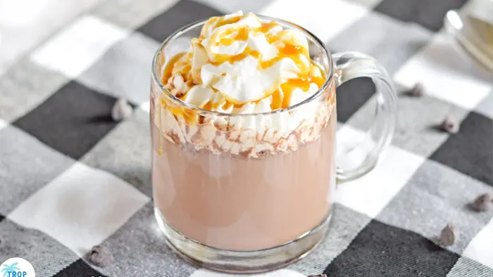 Mug of caramel vodka hot chocolate with whipped cream and caramel sauce on top.