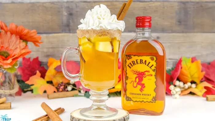 Fireball apple cider in a glass mug with whipped cream on top.