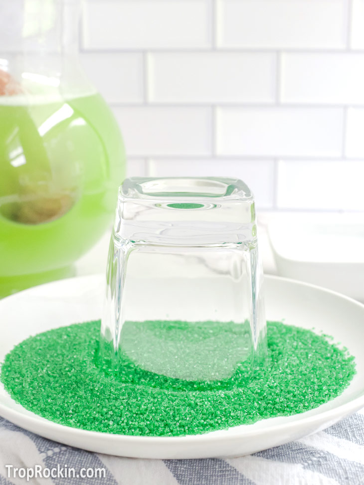 Glass upside down in a small plate filled with green sanding sugar.