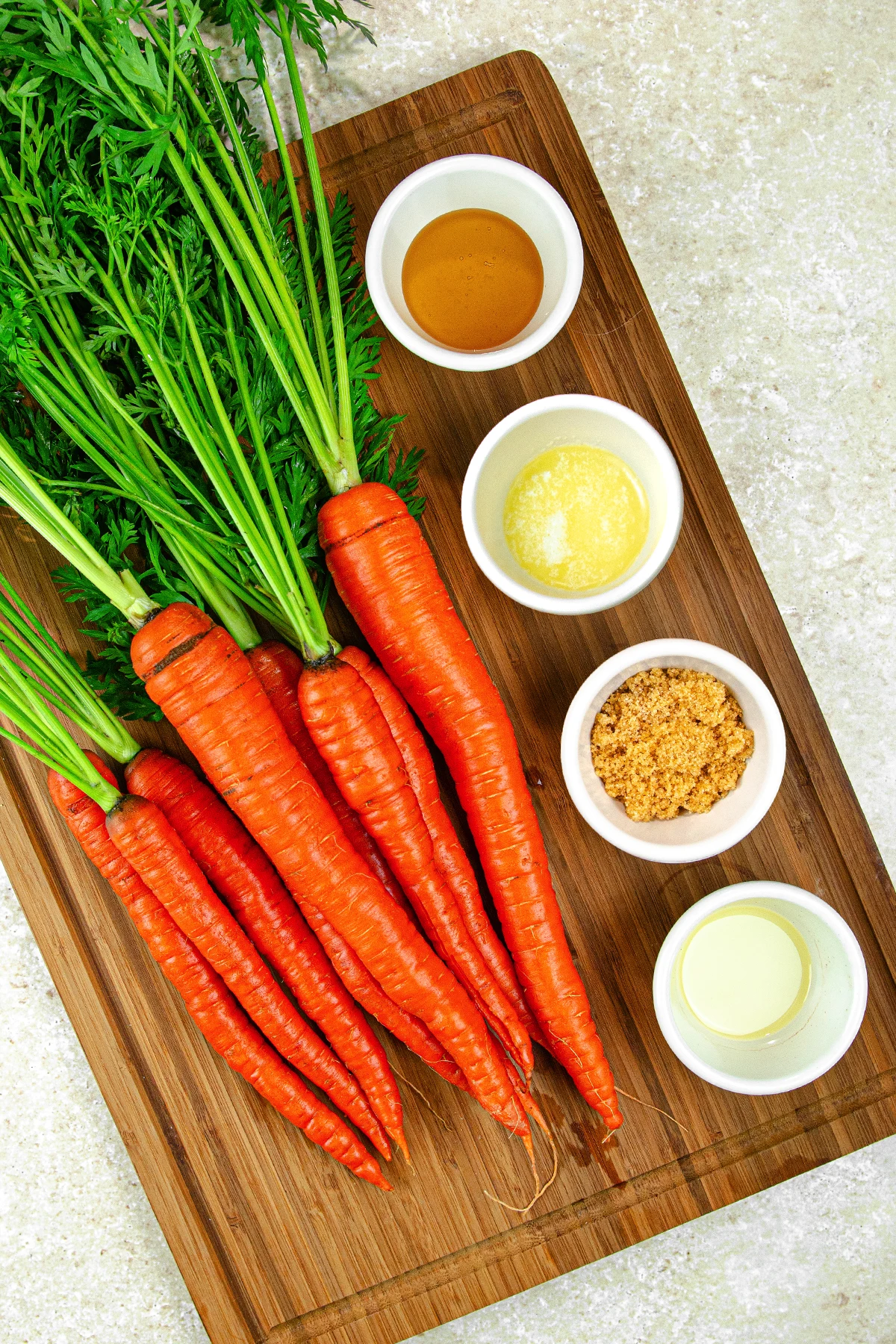 air fryer carrots ingredients. Carrots and ramekins with ingredients inside lined up on a cutting board.