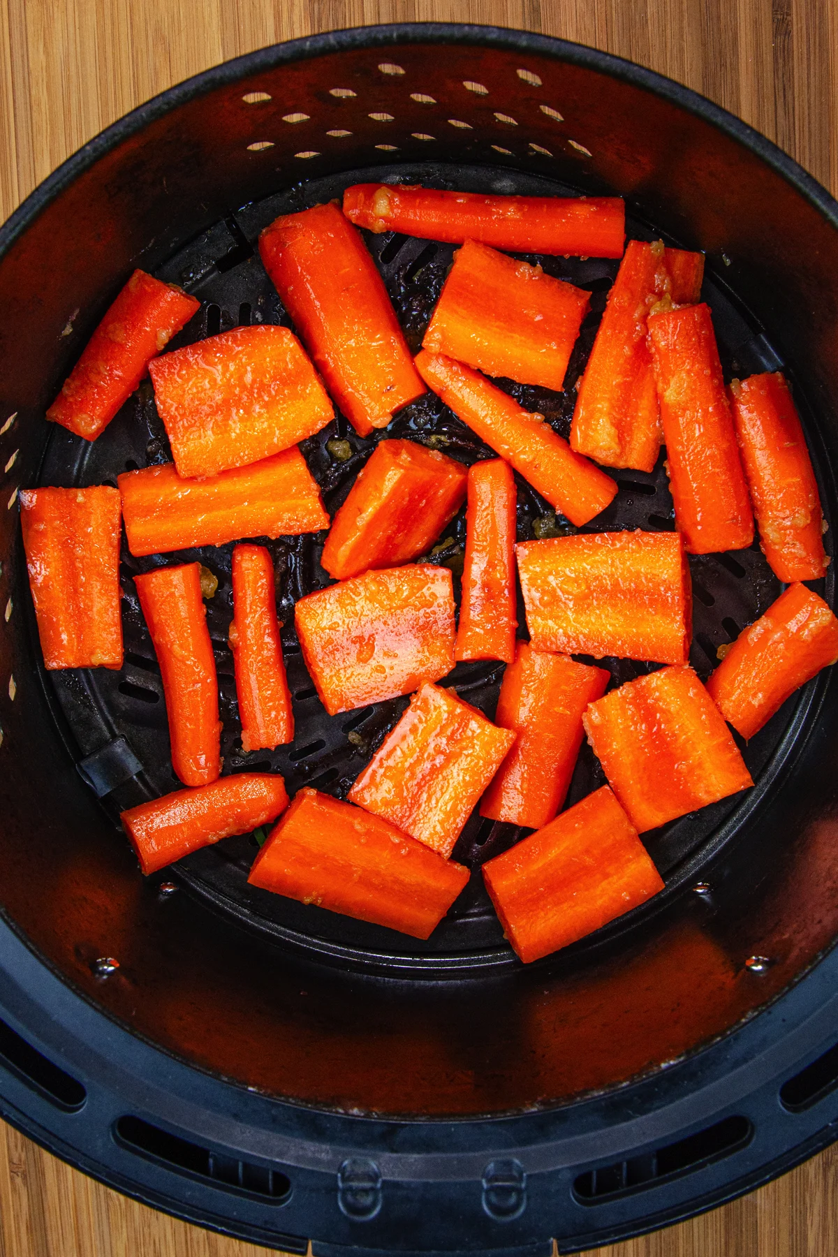 raw carrots in air fryer basket.