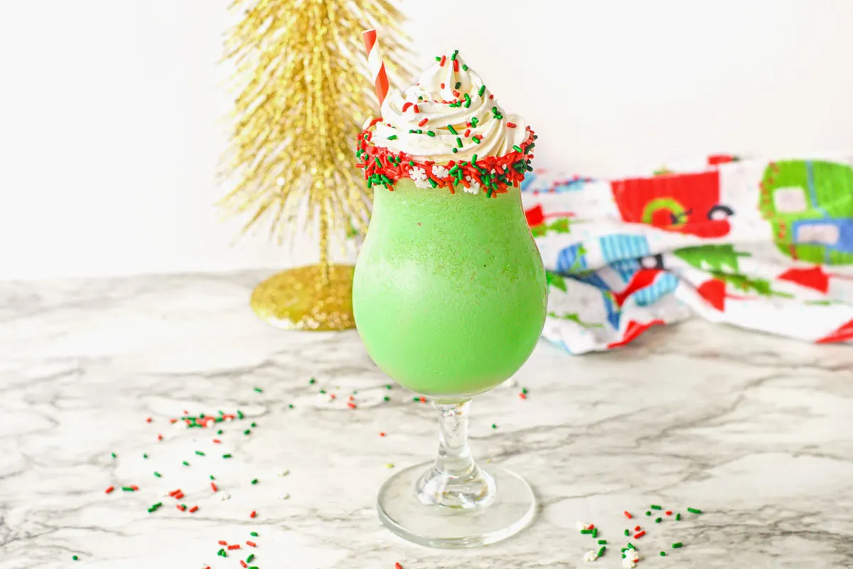 Green Christmas Milkshake with whipped cream on top and Christmas sprinkles.