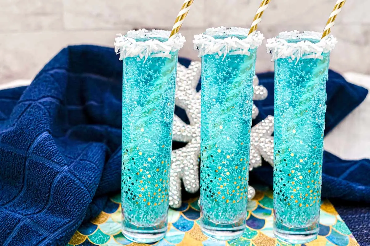 Jack frost mimosas are bright blue with white shredded coconut around the rim of the glasses.