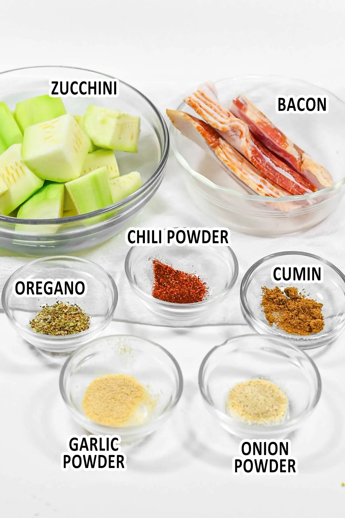 air fryer bacon wrapped zucchini ingredients displayed in bowls on counter top.