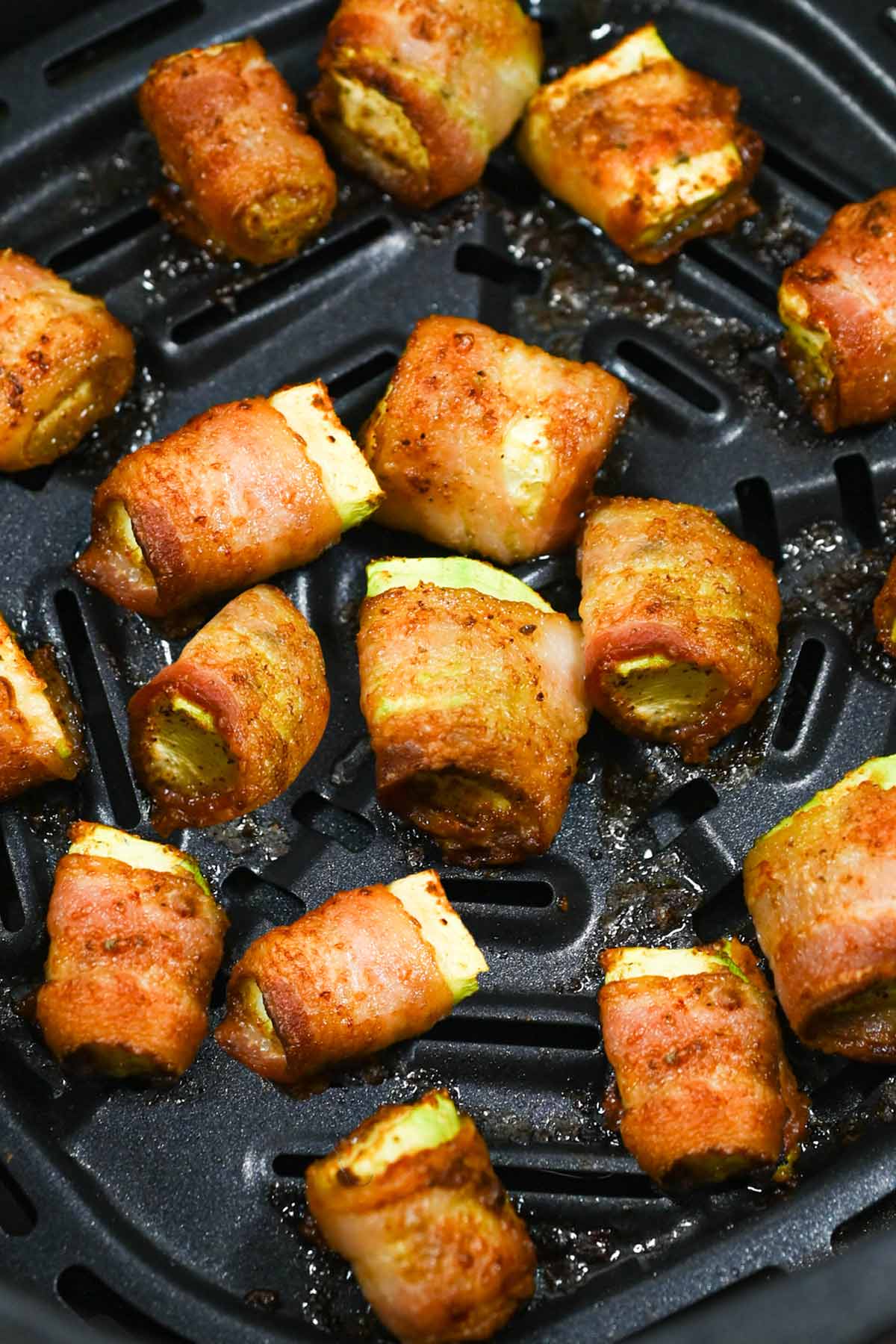 cooked air fryer bacon wrapped zucchini in the air fryer basket.