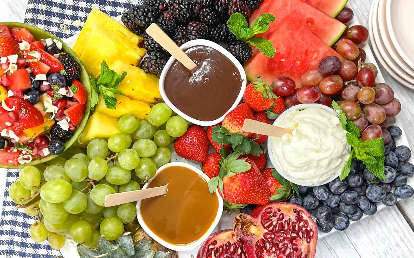 Fruit charcuterie board with 3 fruit dips, a honey glazed fruit salad and variety of fresh fruits.